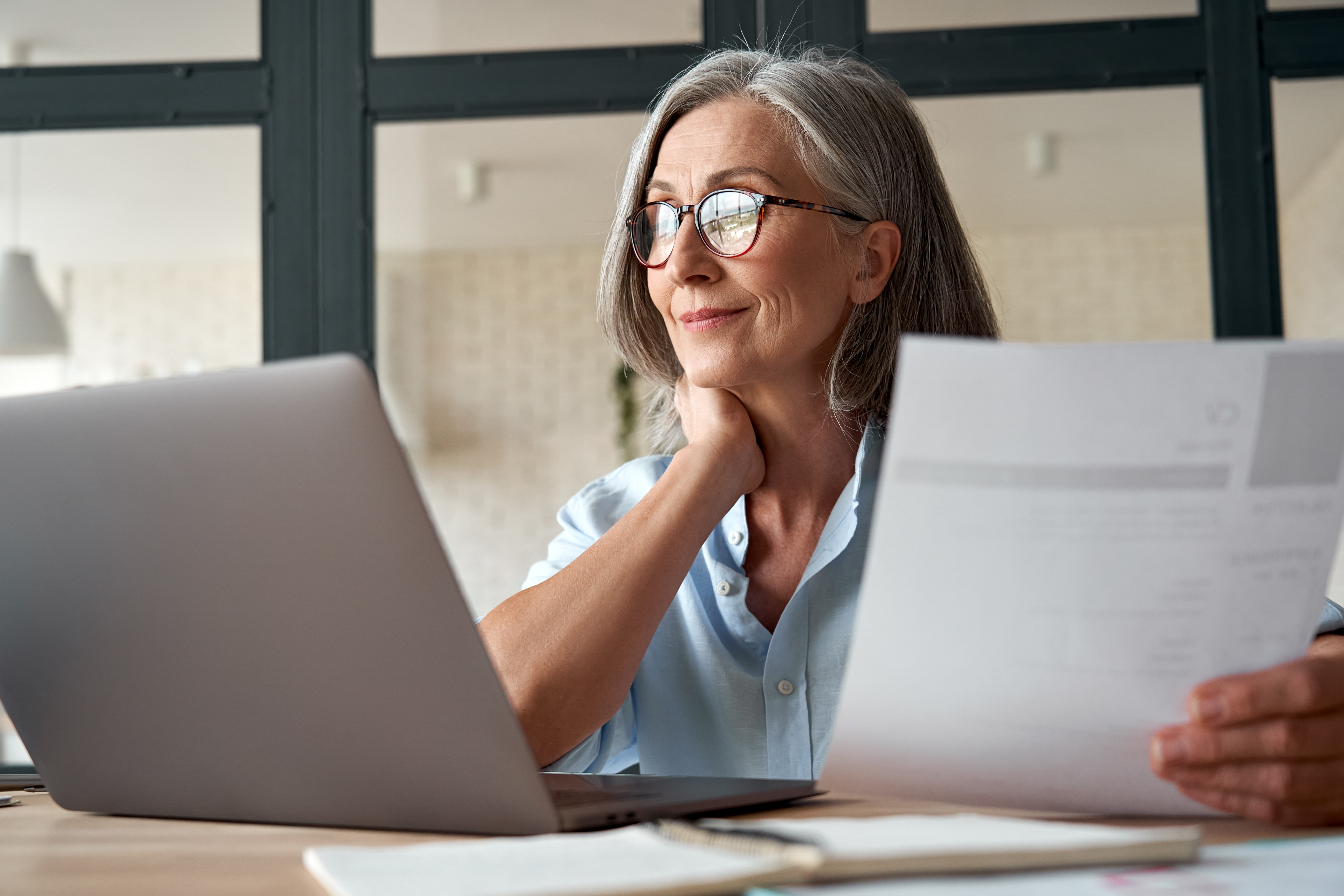 Smiling mature middle aged business woman holding cv searching job online.